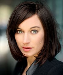 Pippa Nixon smiling, wearing a navy blazer, with shoulder-length brown hair and a neutral background.