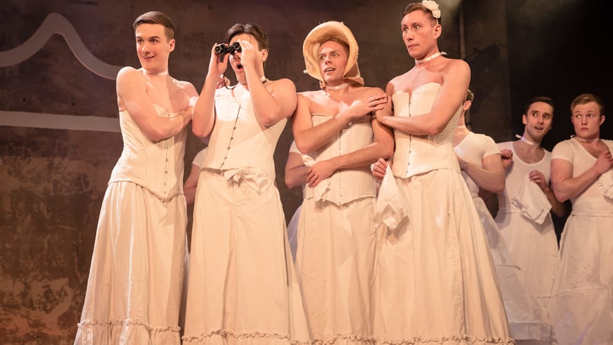A scene from "The Pirates of Penzance" featuring actors in period costumes on stage.