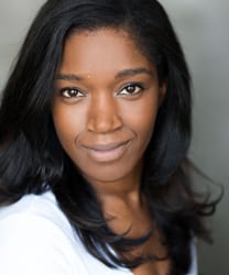 Rachel John smiling, wearing a black top, with long dark hair and a neutral background.