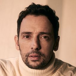 Ralf Little performing on stage in a minimalist set with dramatic lighting.
