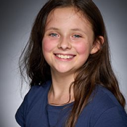 Rhiannon Parry smiling, wearing a costume, with a theatrical backdrop from Harry Potter and the Cursed Child.