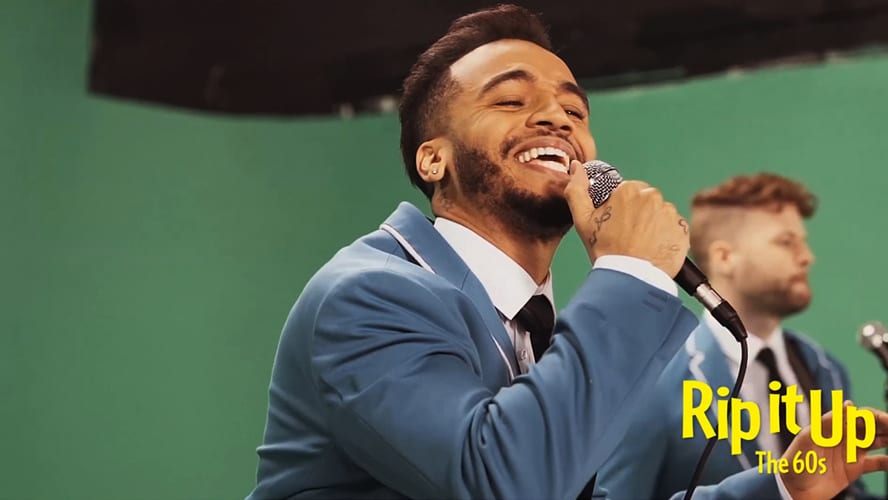 Behind-the-scenes shot of a video production set with crew members and equipment in action.