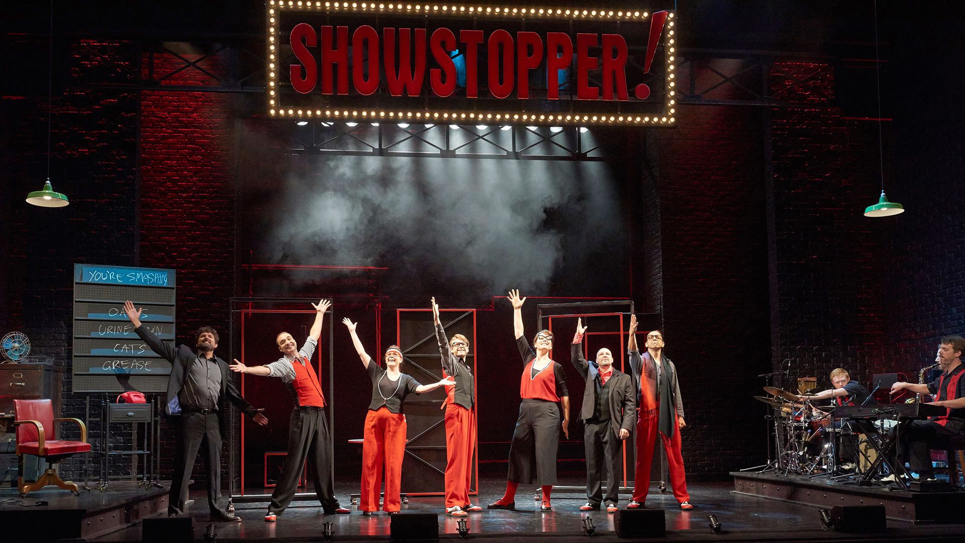 A vibrant stage scene from "SHOWSTOPPER! THE IMPROVISED MUSICAL" with performers in colourful costumes.