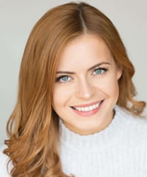 Sophie Evans smiles warmly, wearing a blue blouse and standing against a neutral background.