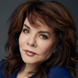 Stockard Channing performing on stage, dressed in a black outfit, with expressive gestures and focused expression.