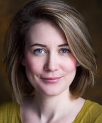 Samantha Sutherland smiling, wearing a blue blouse, with long brown hair and a neutral background.