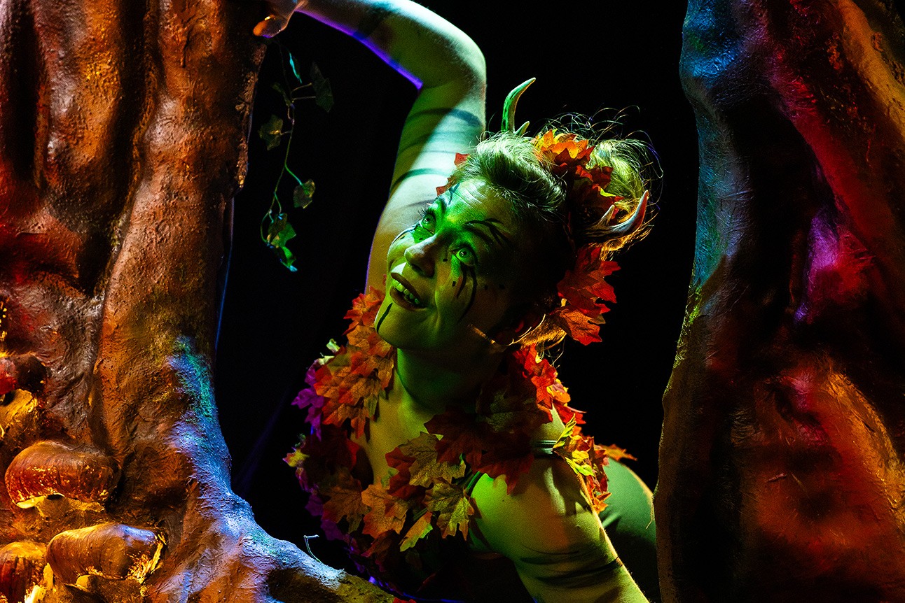 A vibrant stage scene featuring actors in dynamic poses, illuminated by dramatic lighting and colourful backdrops.
