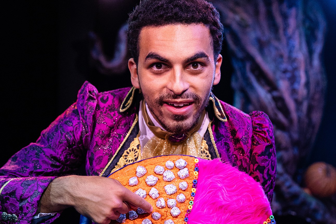 A stage scene featuring actors in dramatic costumes, illuminated by soft, atmospheric lighting.