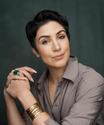 Soophia Foroughi smiling, wearing a professional outfit, with dark hair and a neutral background.