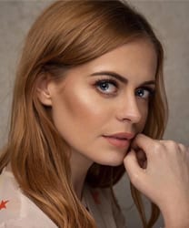 Sophie Evans smiling, with long brown hair and wearing a blue blouse against a neutral background.