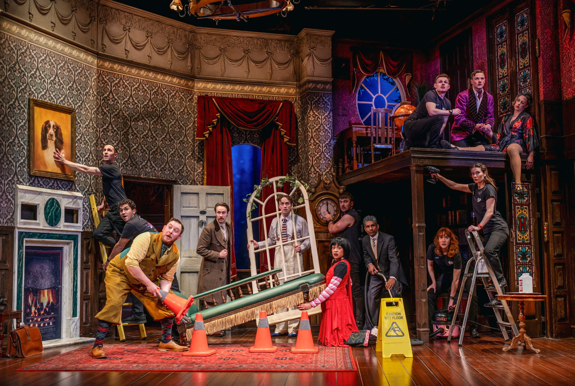 A group of actors in costume performing on stage, with dramatic lighting and set design.