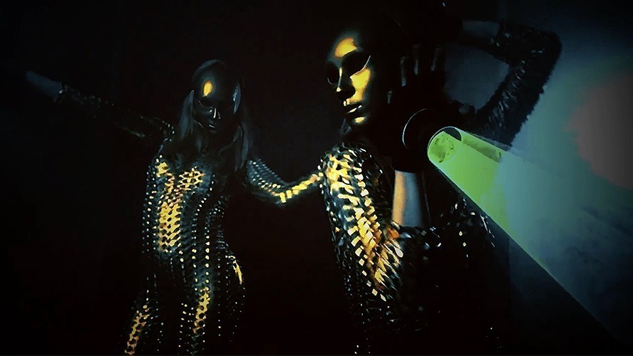 A vibrant stage scene featuring performers in colourful costumes, illuminated by dramatic lighting.