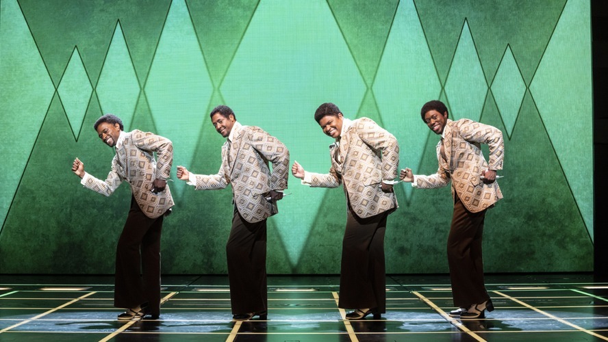 A vibrant stage scene featuring performers in stylish costumes, singing with enthusiasm and energy.