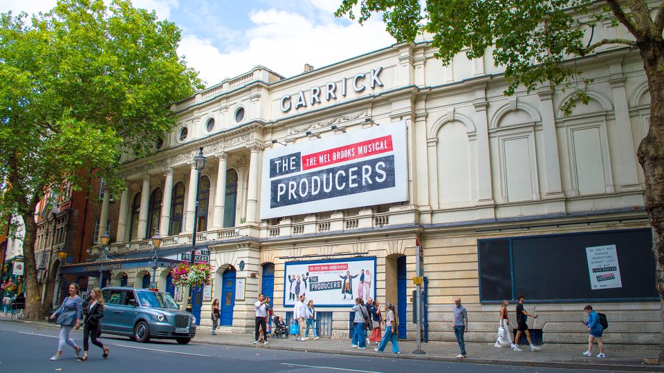 Garrick Theatre exterior featuring a marquee displaying "The Producers" in bright lights.
