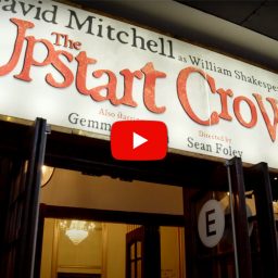 A vibrant still from "The Upstart Crow" featuring characters in Elizabethan costumes on stage.