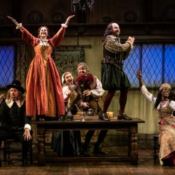 Cast members of "The Upstart Crow" at the Apollo Theatre, dressed in period costumes, smiling.