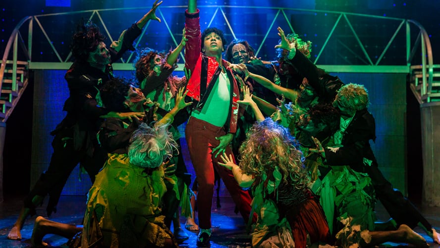 A vibrant stage scene from "Thriller Live," featuring dancers in dynamic poses and dramatic lighting.