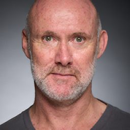 Tim Hibberd in character costume, standing on stage with dramatic lighting and theatrical backdrop.