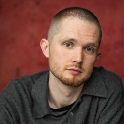 Tom Mahy, a man with short dark hair, smiling against a neutral background.