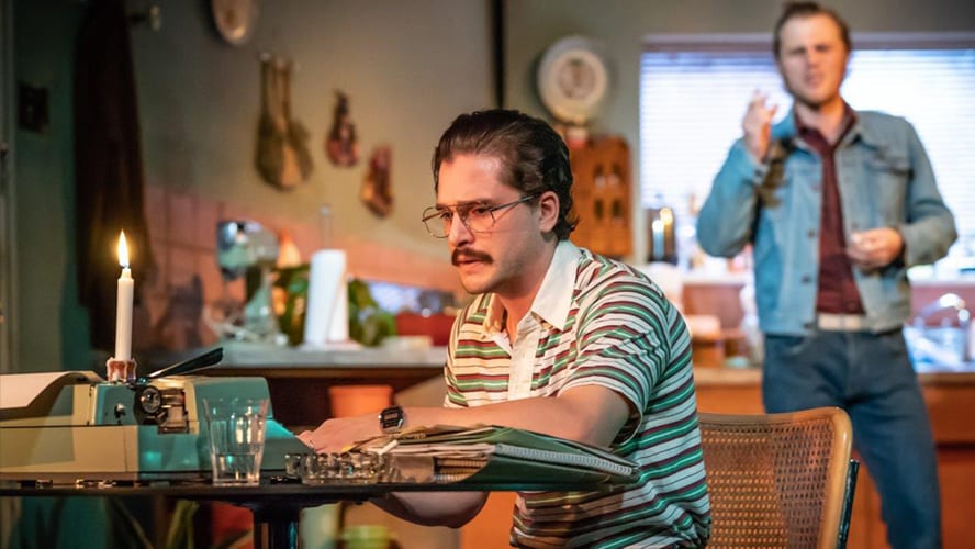 Two actors performing on stage, with a rustic set and dramatic lighting in the background.