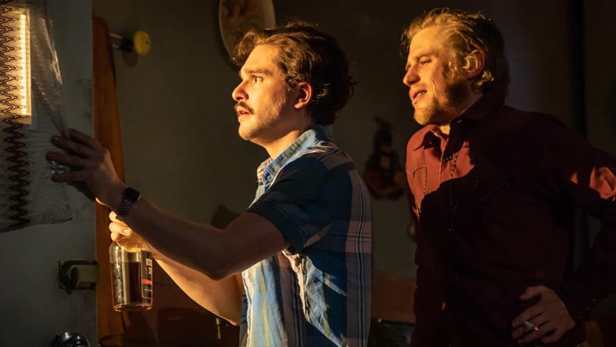 Two actors on stage in a dramatic scene, surrounded by a rustic set and dim lighting.