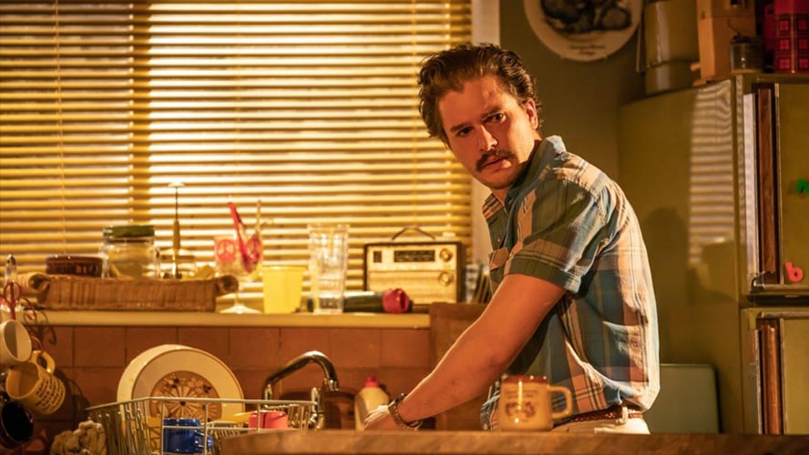 Two actors on stage in a dramatic scene, surrounded by minimalistic set design and warm lighting.