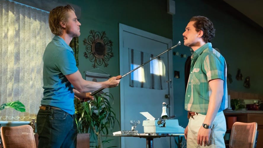 Two actors on stage in a dramatic scene, surrounded by minimalistic set design and warm lighting.