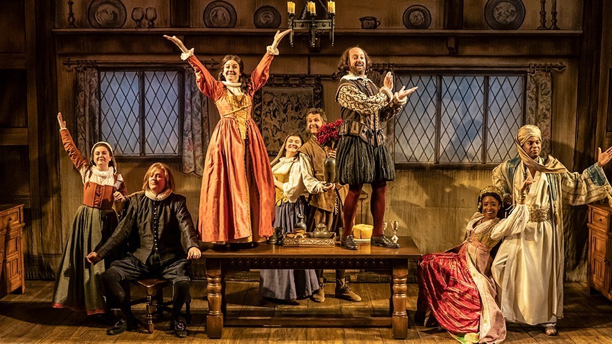 A vibrant stage scene with actors performing under bright lights and an elaborate set design.