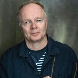Headshot of Jason Watkins, featuring a smiling man with short dark hair and a blue shirt.