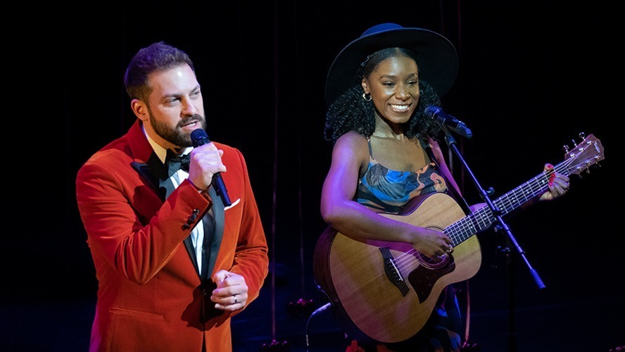 A vibrant stage with performers in elegant costumes singing passionately under dramatic lighting.