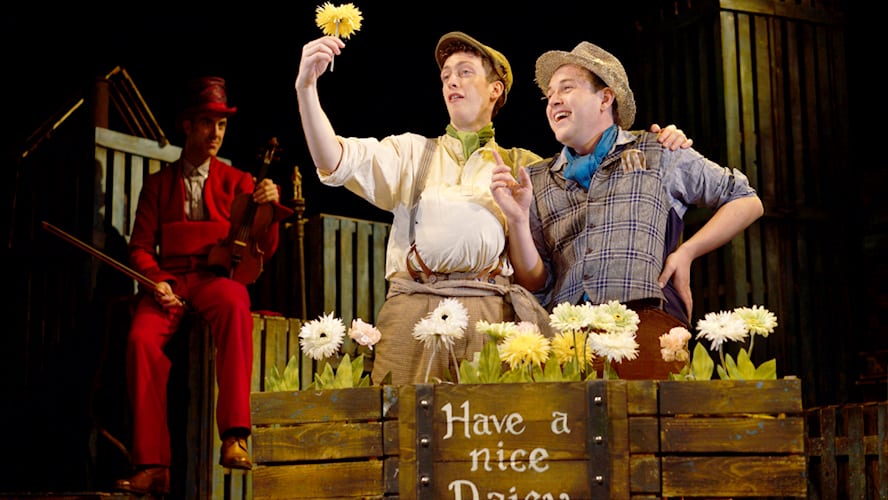 A vibrant stage scene from the Wilde Creatures show, featuring performers in colourful costumes and props.