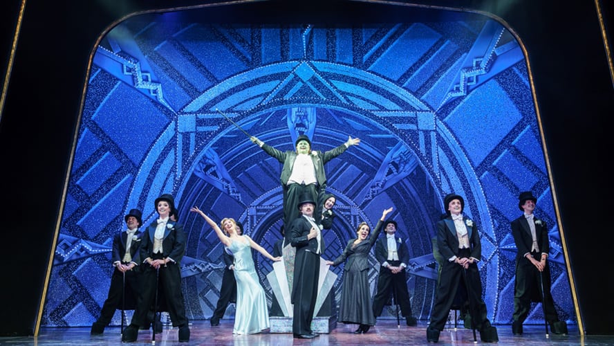 A scene from Young Frankenstein featuring characters in period costumes, with dramatic lighting and props.
