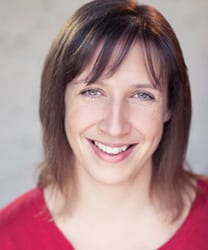 A woman with shoulder-length brown hair, wearing a blue blouse, smiling warmly at the camera.