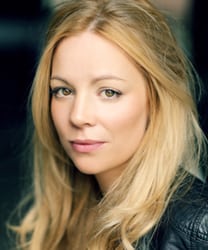 Fiona Button smiling, wearing a black top, with shoulder-length brown hair and natural makeup.