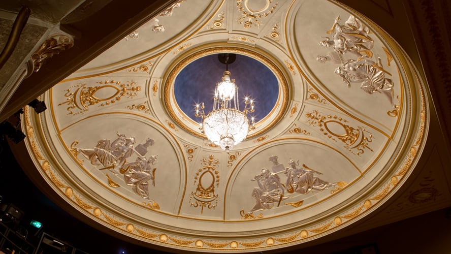 Garrick Theatre exterior featuring a classic façade with ornate detailing and bright marquee lights.