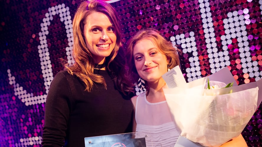 A group of diverse individuals holding awards, smiling and posing together at a formal event.