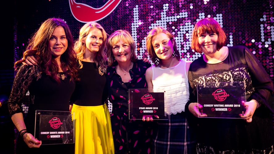 A group of diverse individuals holding awards, smiling, and posing together at a ceremony.
