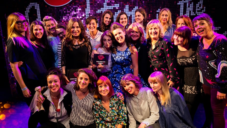 A group of diverse individuals holding awards, smiling and posing together at a formal event.