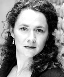 Sioned Jones smiling, wearing a navy blazer, with shoulder-length brown hair and a neutral background.