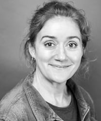 Sophie Thompson smiling, with shoulder-length brown hair and wearing a black top against a neutral background.