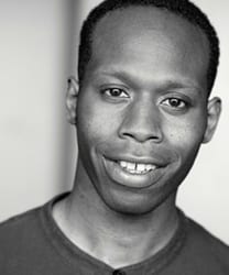 Sydney K. Smith smiling, wearing a blue blazer and white shirt, with a blurred background.