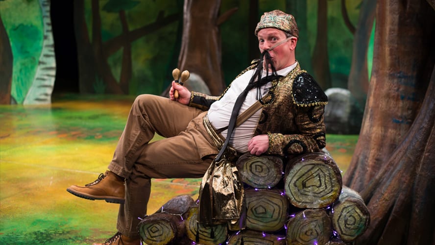 A large, friendly Gruffalo character stands in a forest, surrounded by trees and foliage.