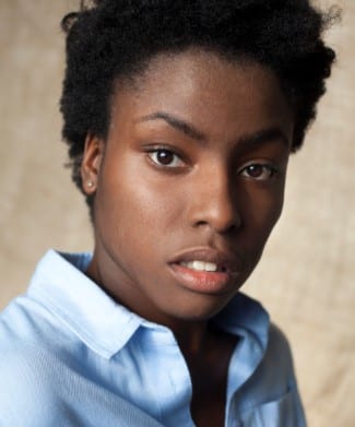 Headshot of Farrell Cox, featuring a smiling individual with short dark hair and a blue shirt.