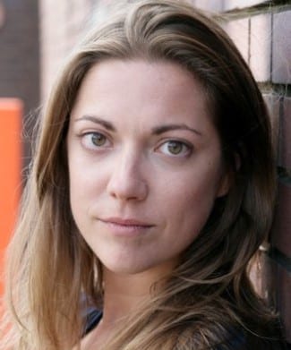 Ruth Everett smiling, with shoulder-length brown hair and a dark blazer against a neutral background.