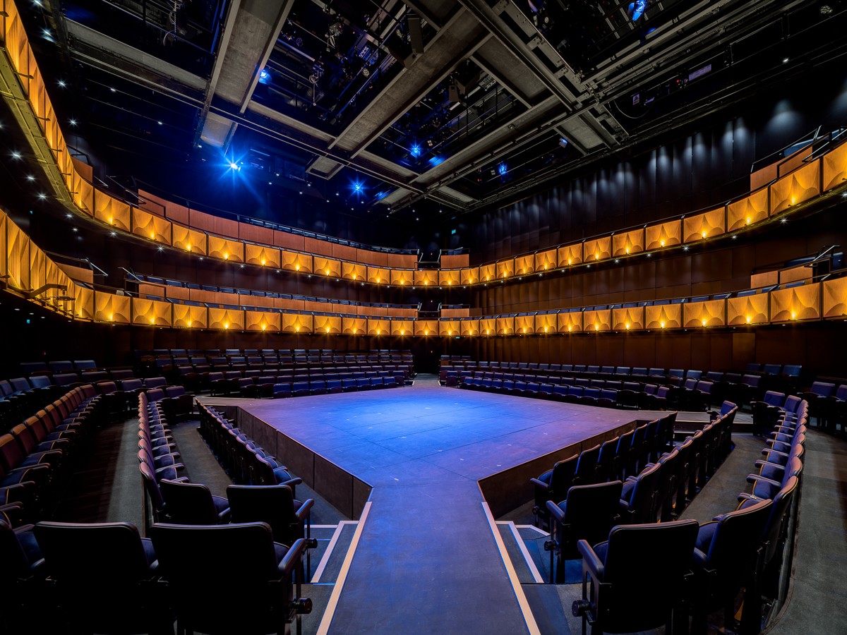 A modern theatre interior featuring plush seating, elegant lighting, and a spacious stage area.