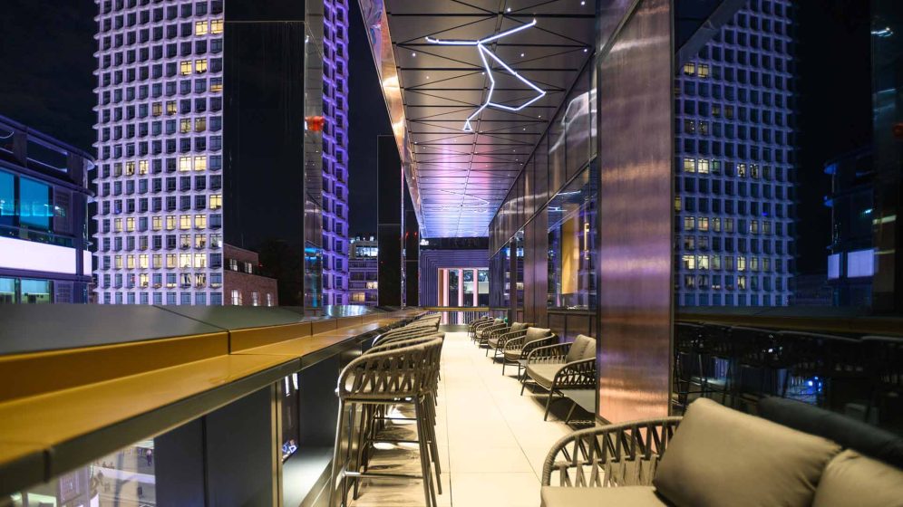 A modern theatre interior featuring plush seating and a vibrant stage illuminated with colourful lights.