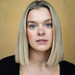 Esme Kennedy smiling, with shoulder-length brown hair and a dark blazer against a neutral background.
