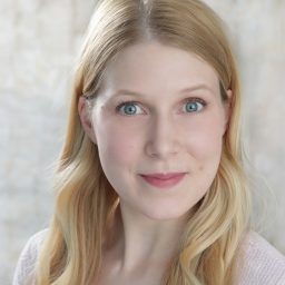 Hannah with brown hair, smiling, wearing a green top against a neutral background.
