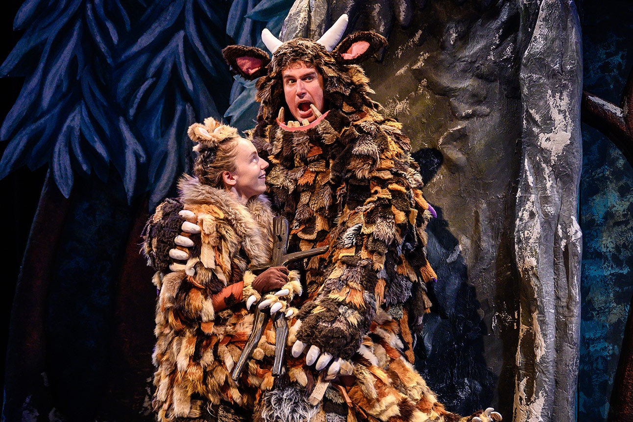 The Gruffalo's Child stands in a snowy forest, surrounded by trees and soft falling snowflakes.