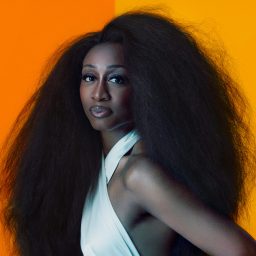 Beverley Knight smiling, with shoulder-length dark hair and a black top against a neutral background.